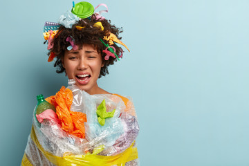 Cleaning up concept. Sorrowful Afro woman with curly hairstyle, cries from despair, wrapped in...