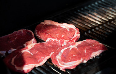 Beef steak cooking. Rib eye steak. Raw meat. Juicy marbled meat on BBQ grill. Medium rare meat roasting
