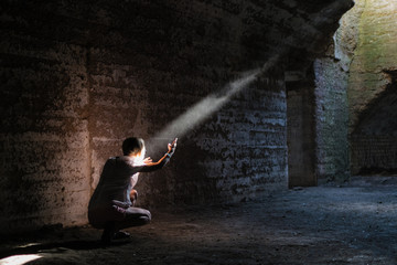 A woman in a dark cave illuminated by a ray of light.