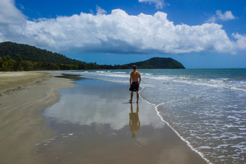 young man walking on the beach in Cape Tribulation in Daintree National Park in the far tropical...