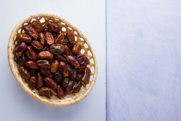 Dried dates on white background. Holy month of Ramadan, concept. Righteous Muslim lifestyle. Starvation. Dates in wooden basket. Vegetarian food. Copy space