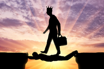 Selfish man with a crown on his head is walking over a man in the form of a bridge over an abyss