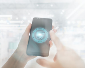 Shopping basket on a mobile phone screen. Woman Hand holding mobile phone on Supermarket blur background
