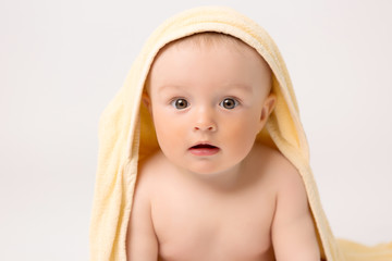 oddler boy with yellow towel on head on white background, Portrait of cute Caucasian newborn baby. The child is wrapped in a yellow soft towel after bathing. Clean and happy little baby in after wash