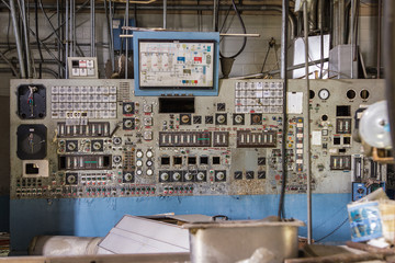 Abandoned control board with a lot of gauges, buttons and knobs left abandoned in a factory