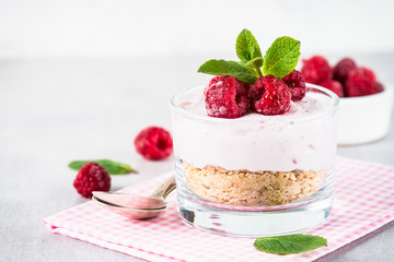No baked cheesecake with raspberry in glass jar.