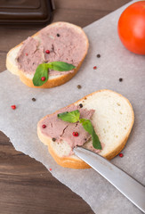 2 sandwiches with chicken pate and Basil sprig, pepper, knife, tomato on wooden surface