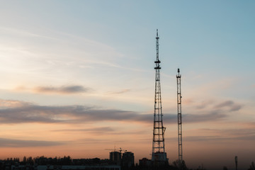 Silhouette, telecommunication towers with TV antennas and satellite dish in sunset, panorama...
