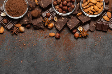 Heap of broken chocolate pieces and nuts on dark concrete background