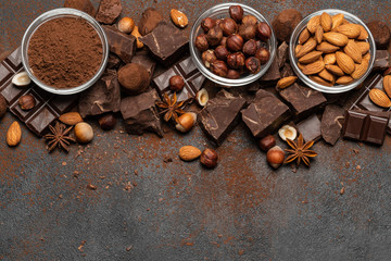 Heap of broken chocolate pieces and nuts on dark concrete background