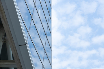 Fototapeta na wymiar Cloud reflected on blue glass windows of building, Divided in half the building and the sky.