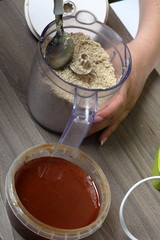 Honey in a container. Near in a blender chopped peanuts and sunflower seeds. Ingredients and tools for making halva.