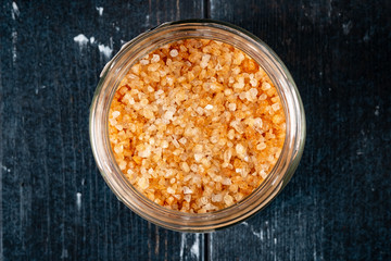 Smoked sea salt in a glass bowl on a dark wooden background, fragrant seasonings for meat and fish. Top view