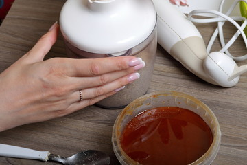 Honey in a container. Near in a blender chopped peanuts and sunflower seeds. Ingredients and tools for making halva.