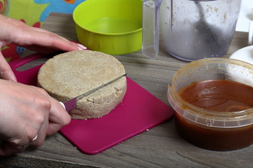 A woman cuts with a knife halva made of honey, peanuts and sunflower seeds. Next honey in the container. Ingredients and tools for making halva.