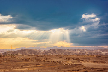 Fototapeta na wymiar Sun lights in rainy clouds in egyptian desert