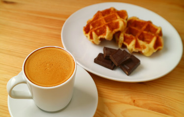 Closed Up Espresso Coffee with Blurry Belgian Waffles and Dark Chocolate Cubes in Background