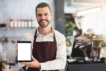 Male barista holding and showing a digital tablet.