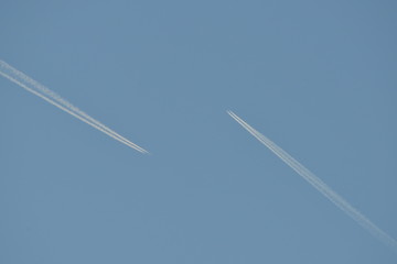 Commercial aircraft at very high altitude with white contrail on cloudless blue sky