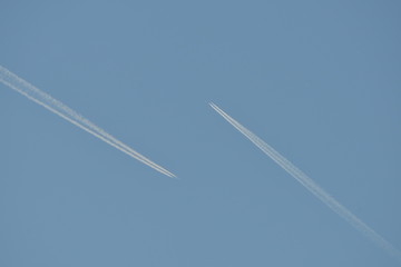 Commercial aircraft at very high altitude with white contrail on cloudless blue sky