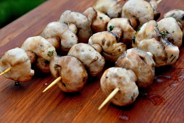 Mushrooms on a wooden skewer, picnic, wooden background.