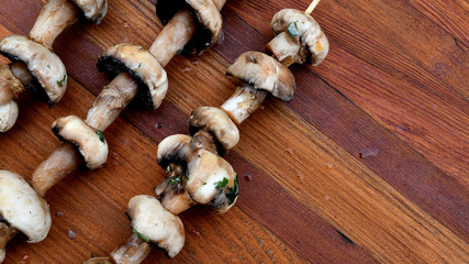 Mushrooms on a wooden skewer, picnic, wooden background.