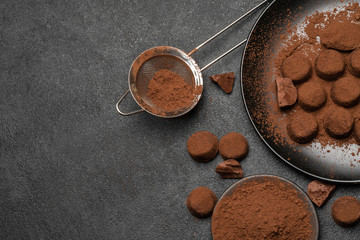Chocolate truffles candies and cocoa powder on dark concrete background