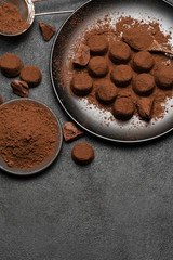 Chocolate truffles candies and cocoa powder on dark concrete background