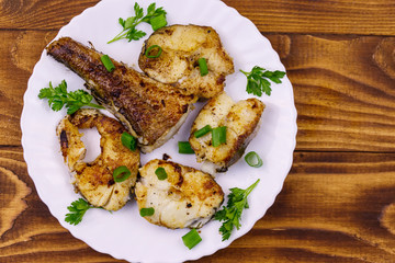 Roasted pollock in white plate on a wooden table