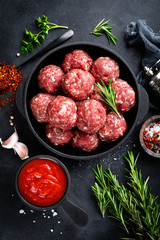 Fresh raw beef meatballs with spices and tomato sauce