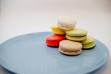 collection of colorful French  Macarons are next to each other on a blue plate on white background