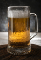 Mug of fresh light beer on wooden background