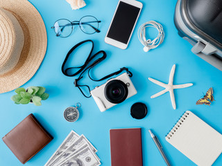 top view travel concept with digital camera, smartphone, map, passport, compass and Outfit of traveler on blue background, Tourist essentials, vintage tone effect