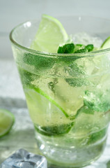 Mojito cocktail with slices of lime and mint leaves in highball glass on a wood table. White background.