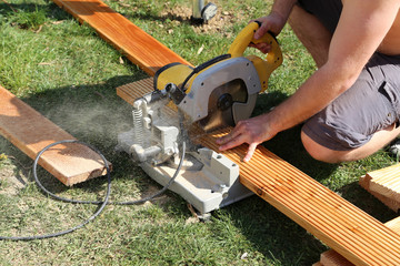 A worker saw wood with a chop saw