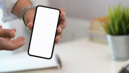Anonymous man showing blank screen mobile smart phone on workspace