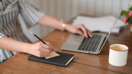 Businesswoman sitting at office and writing on sticky paper notes on desk