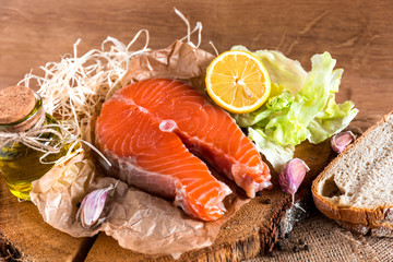  fresh raw salmon steaks with  lemon and olive oil on black brown background. Healthy food, diet concept. Preparation for cooking fish with spices.
