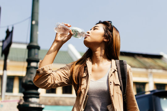 Young Beautiful Asian Female Tourist Woman Drinking Water From Plastic Bottle In City Of Bangkok, Thailand