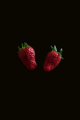Fresh strawberry berries on a black background. Vertical orientation