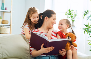 mother reading a book to daughters