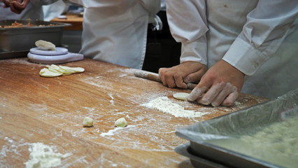 Closeup of making process of Chinese dumpling inside the kitchen. Hand preparations including pastry massage and mince pork, prawn, vegetable wrap.Selected focus.