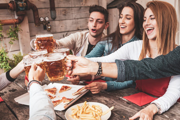 Happy group of friends drinking beer and eating pizza