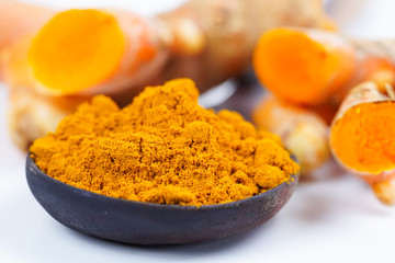 Turmeric roots and powder herb on wooden background.