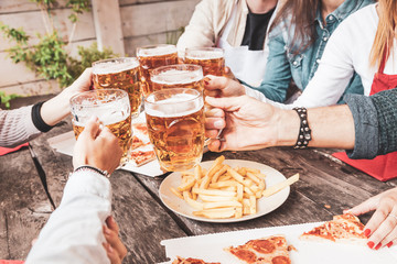 group of happy friends drinking beer and eating take away pizza