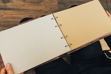 The guy holds an empty vintage book made of wood
