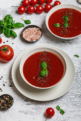 Traditional Spanish cold tomato soup gazpacho in a white bowl on a grey stone background. Traditional Spanish food. Concept of Spanish cold soup made of ripe tomatoes. Copy space, top view soup. 