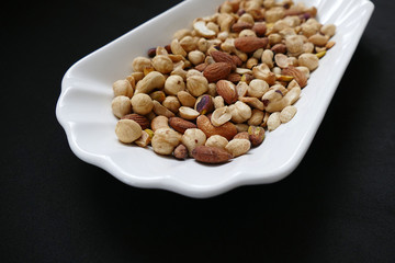 nuts, cashew nuts, dry almonds all close up on a plate, dry foods on black ground, nuts,