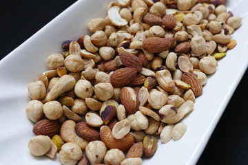 nuts, cashew nuts, dry almonds all close up on a plate, dry foods on black ground, nuts,
