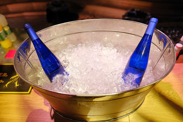Bottles of white wine on ice and nearby empty glasses for wine